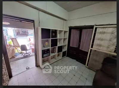 Cozy interior space with tiled flooring and shelving unit, ideal for storage or small office setup.