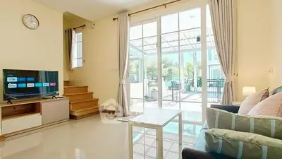 Bright living room with modern decor and large glass doors leading to a sunny patio.