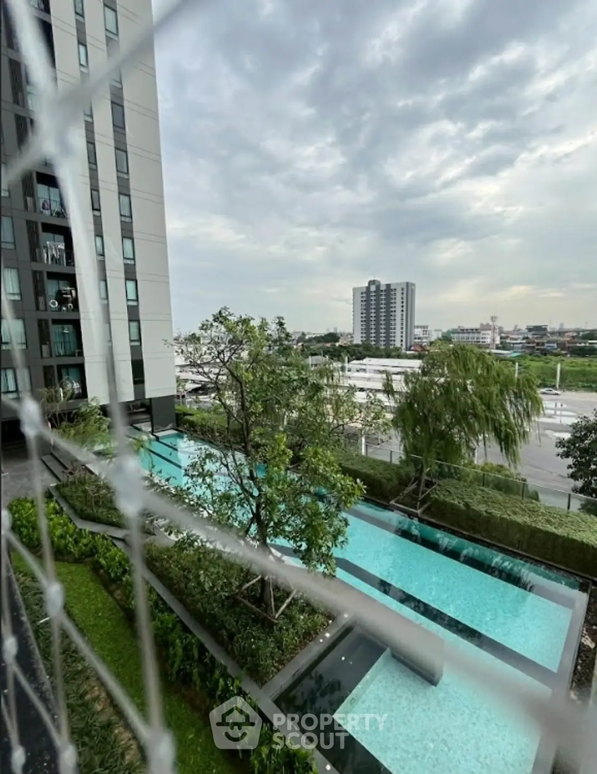 Modern condominium with pool and lush greenery offering serene city views.
