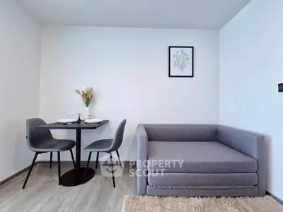 Modern minimalist living room with sleek grey furniture and dining area.