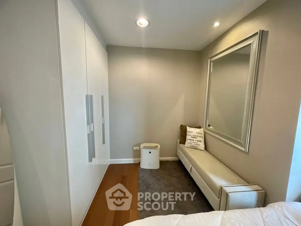 Stylish bedroom with modern wardrobe and elegant seating area, perfect for relaxation and storage.