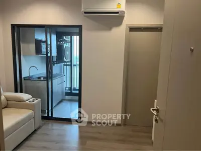 Modern apartment interior with sleek kitchen and balcony view, featuring air conditioning and stylish flooring.