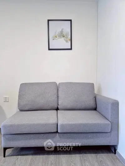 Modern gray sofa in a minimalist living room with framed art on white wall.