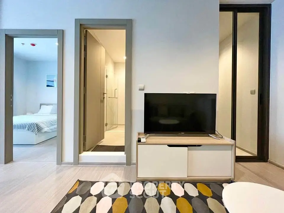Modern living room with TV, adjacent bedroom and bathroom, stylish decor