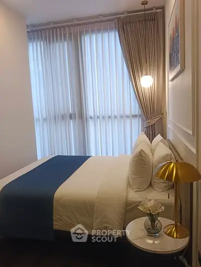 Cozy bedroom with elegant decor and natural light through sheer curtains.