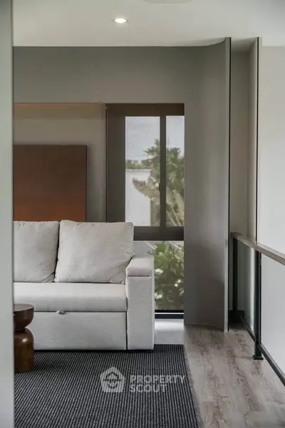 Modern living room with sleek design and large window offering a serene view.