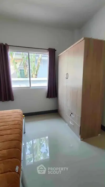 Cozy bedroom with wardrobe and window view, perfect for relaxation.