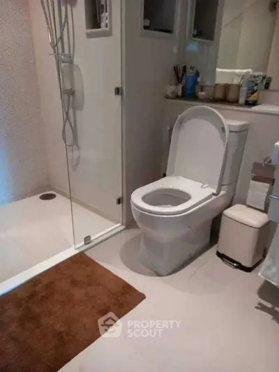 Modern bathroom with shower and toilet, featuring sleek design and neutral tones.