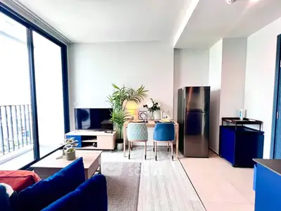 Modern living room with open kitchen, stylish furniture, and large windows for natural light.