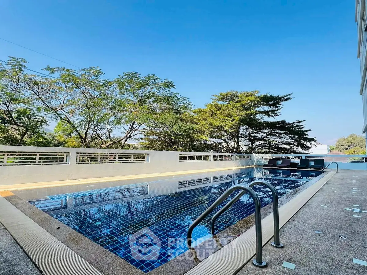 Luxurious outdoor pool with serene surroundings and clear blue sky, perfect for relaxation and leisure.