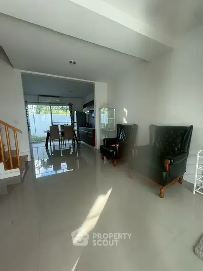 Spacious living room with elegant armchairs and modern dining area, perfect for family gatherings.