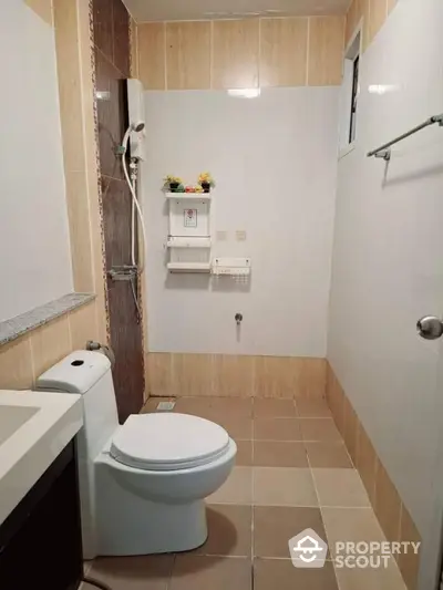 Modern bathroom with sleek design and neutral tiles, featuring a shower and toilet.