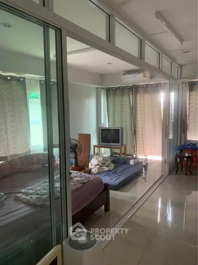 Spacious bedroom with glass partition, natural light, and modern furnishings for a cozy living experience.