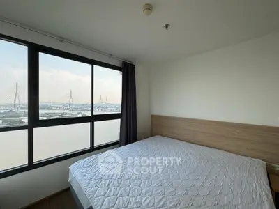 Spacious bedroom with large window offering stunning city and bridge view