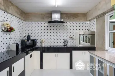 Modern kitchen with sleek black and white design, featuring built-in appliances and stylish backsplash.