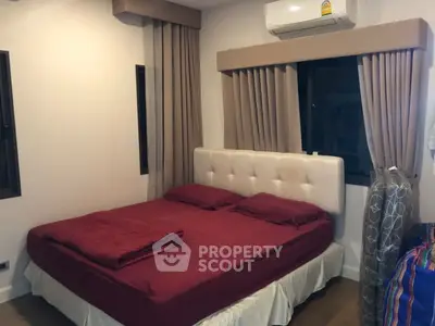 Cozy bedroom with plush red bedding and elegant curtains, featuring a modern air conditioning unit.