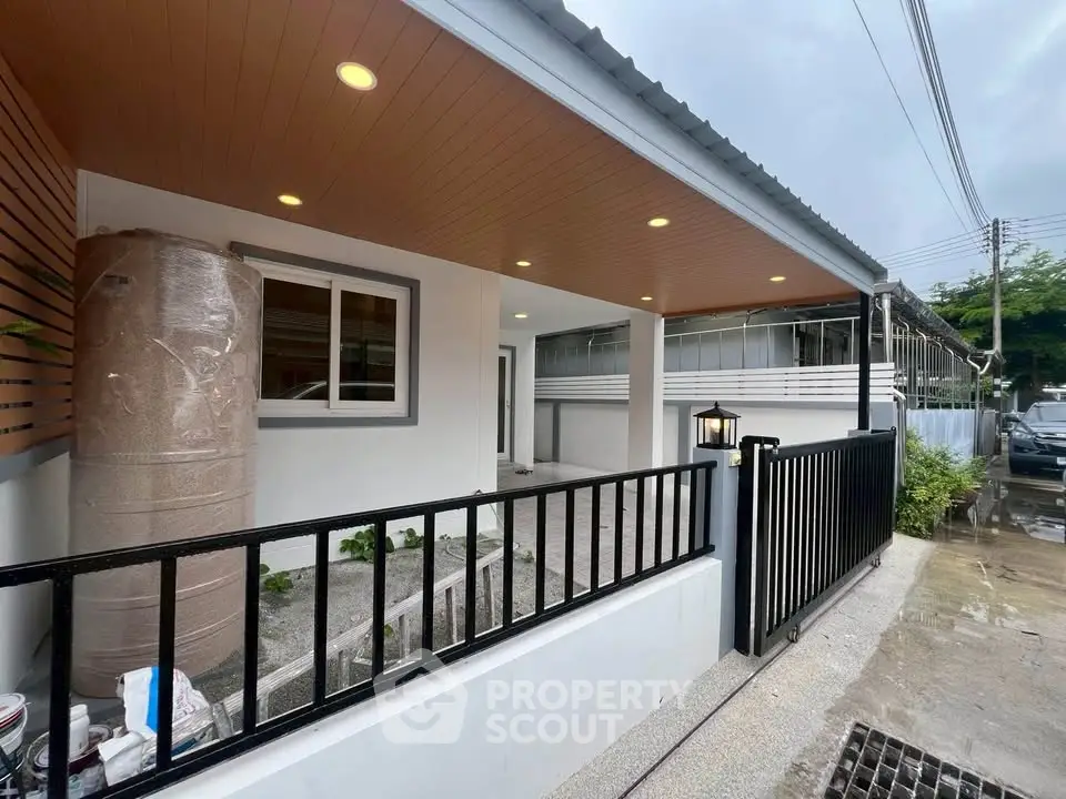 Modern single-story home with sleek exterior and gated entrance, featuring a covered porch and contemporary design.