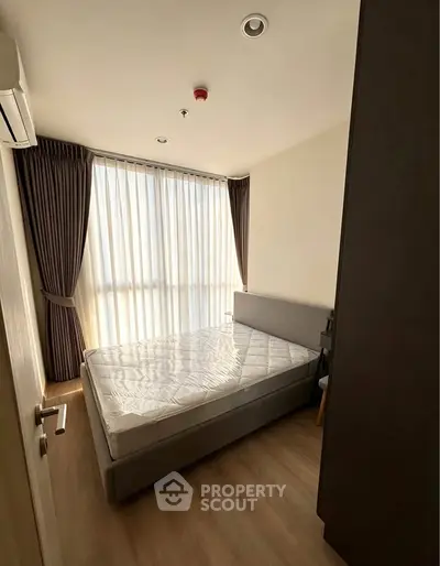 Cozy bedroom with natural light and modern furnishings in a stylish apartment.