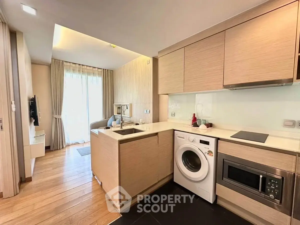 Modern open-layout kitchen with washing machine and microwave in a stylish apartment