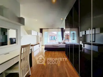 Spacious modern bedroom with sleek black wardrobe and large windows offering natural light.