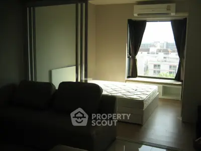 Modern apartment interior with cozy living area and bright bedroom featuring large window view.