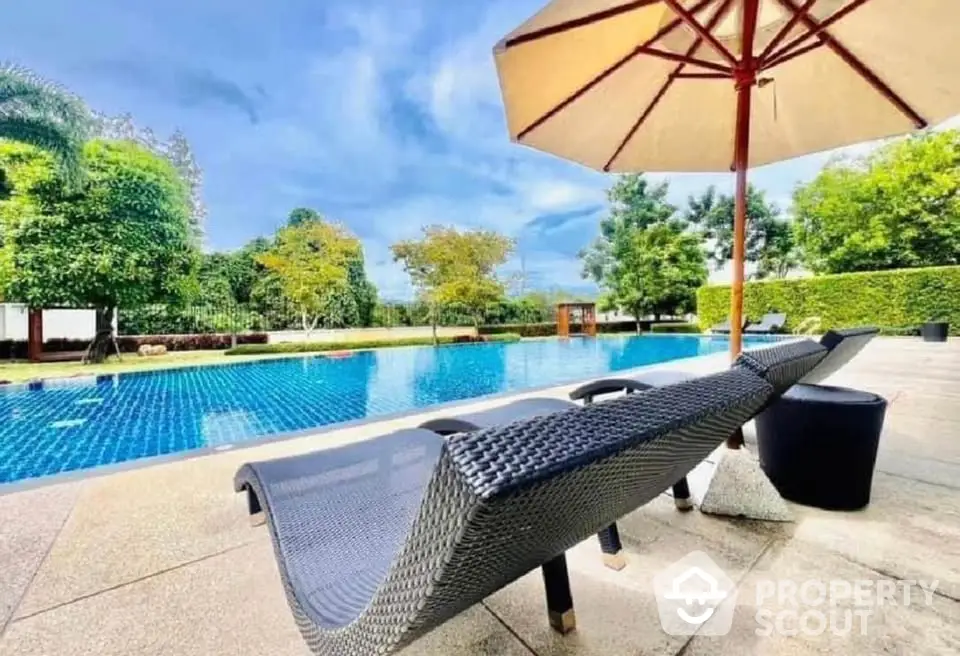 Luxurious outdoor pool area with sun loungers and umbrella, perfect for relaxation and leisure.