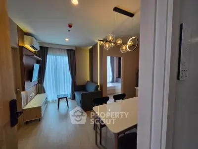 Modern living room with stylish lighting and open layout, featuring a cozy sofa and wall-mounted TV.