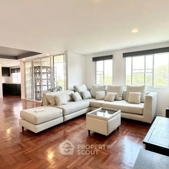 Spacious living room with elegant parquet flooring and large windows for natural light.