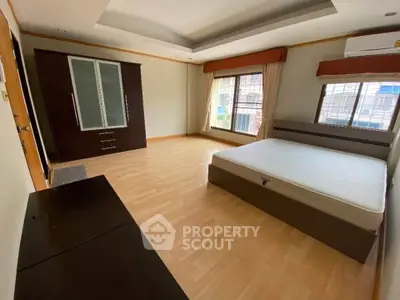 Spacious bedroom with wooden flooring and large windows in modern apartment.
