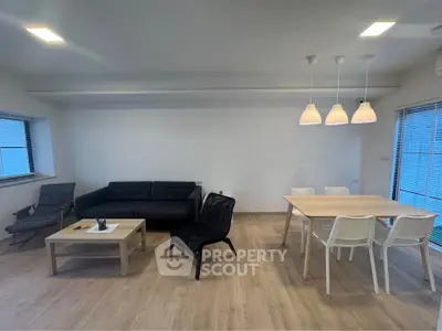 Modern living room with sleek furniture and dining area, featuring minimalist design and ample natural light.