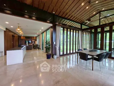 Luxurious open-plan living and dining area with garden view, featuring elegant marble flooring and modern furnishings.