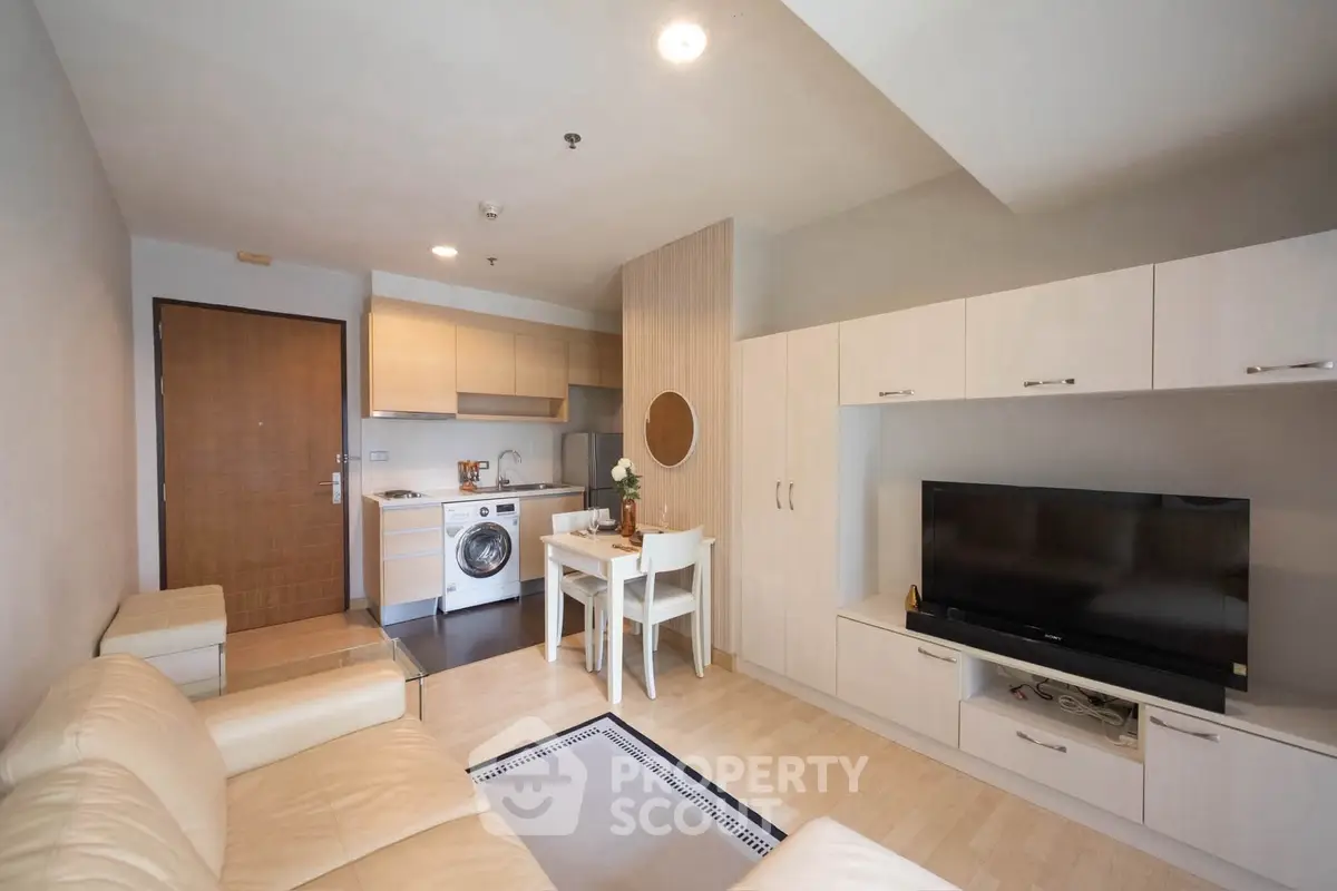 Modern living room with open kitchen, featuring sleek furniture and integrated appliances.