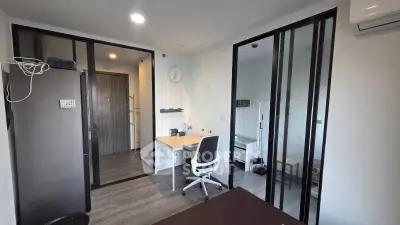 Modern study room with sleek design and ample natural light, featuring a desk, chair, and sliding glass doors.