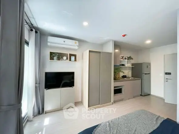 Modern studio apartment with sleek kitchen and cozy living area, featuring natural light and stylish decor.