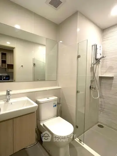Modern bathroom with glass shower and sleek fixtures in contemporary apartment.