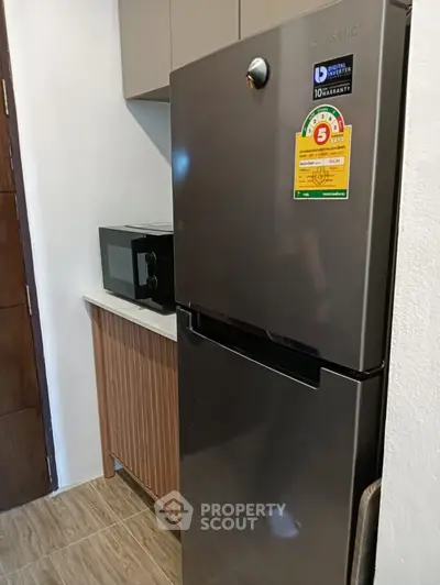 Modern kitchen with sleek fridge and microwave in compact layout.