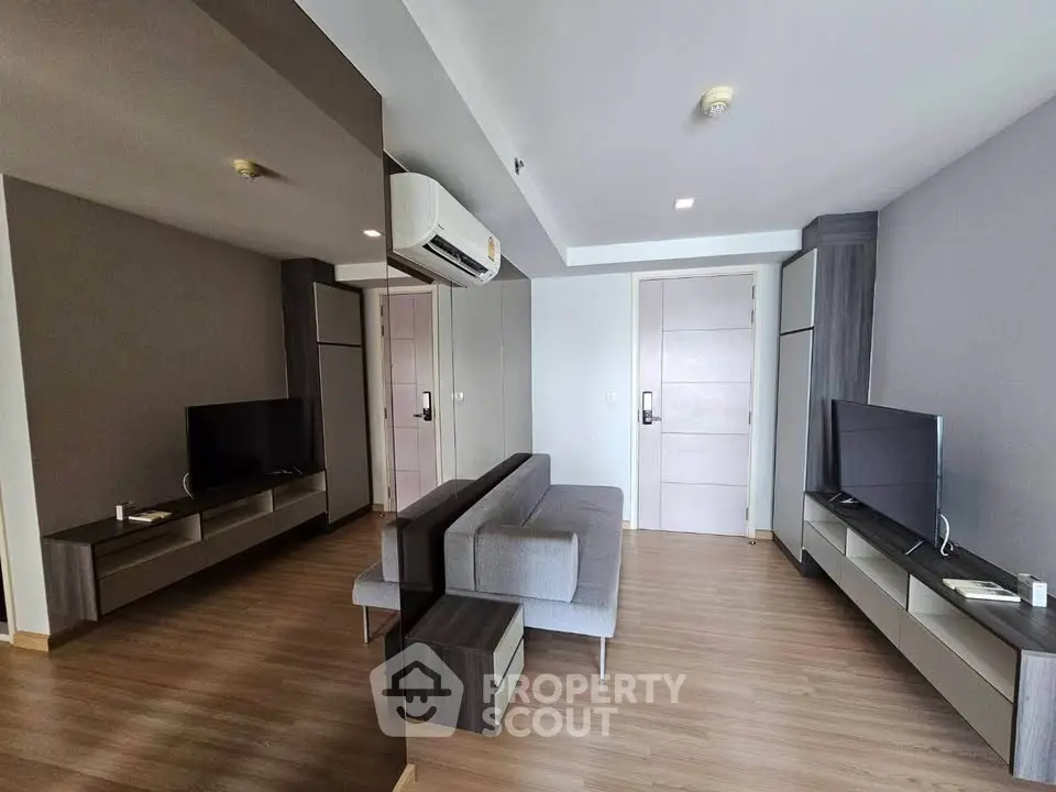 Modern living room with sleek furniture and dual TVs in a stylish apartment.