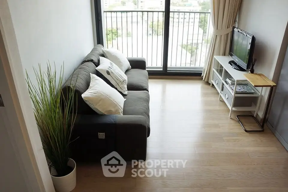 Modern living room with balcony view, featuring cozy sofa and sleek TV setup.
