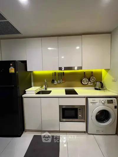 Modern kitchen with sleek white cabinets, built-in appliances, and ambient lighting