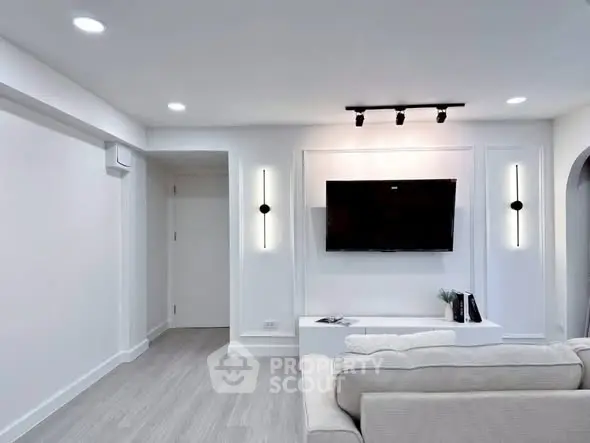 Modern living room with sleek design, featuring a wall-mounted TV and stylish lighting.