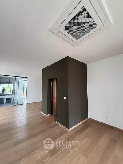 Spacious modern living room with sleek wooden flooring and built-in air conditioning.