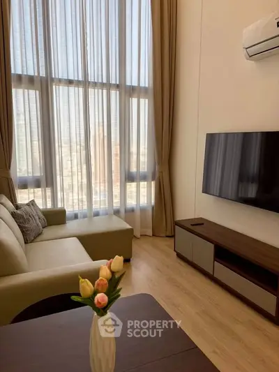 Modern living room with large windows, cozy sofa, and wall-mounted TV in a high-rise apartment.