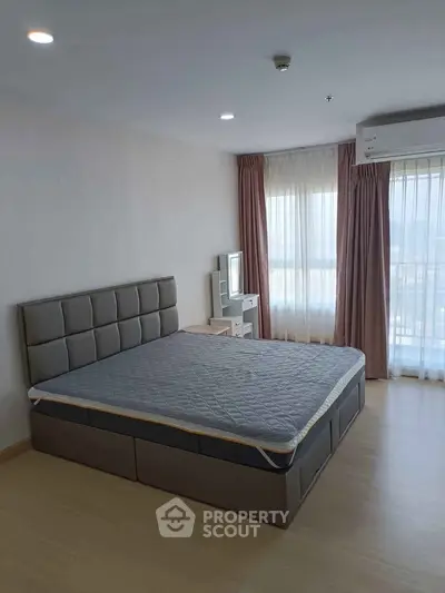 Spacious bedroom with modern decor and large windows offering natural light.