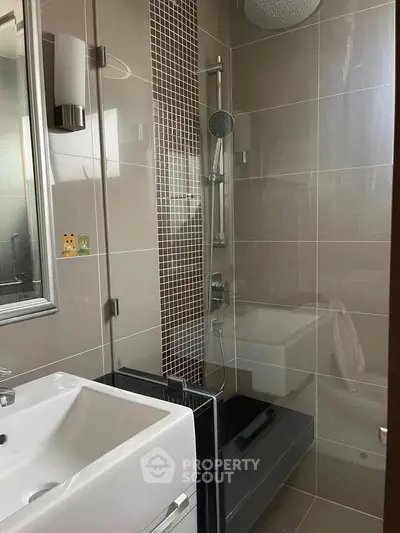 Modern bathroom with sleek fixtures and stylish tile design, featuring a shower and sink area.