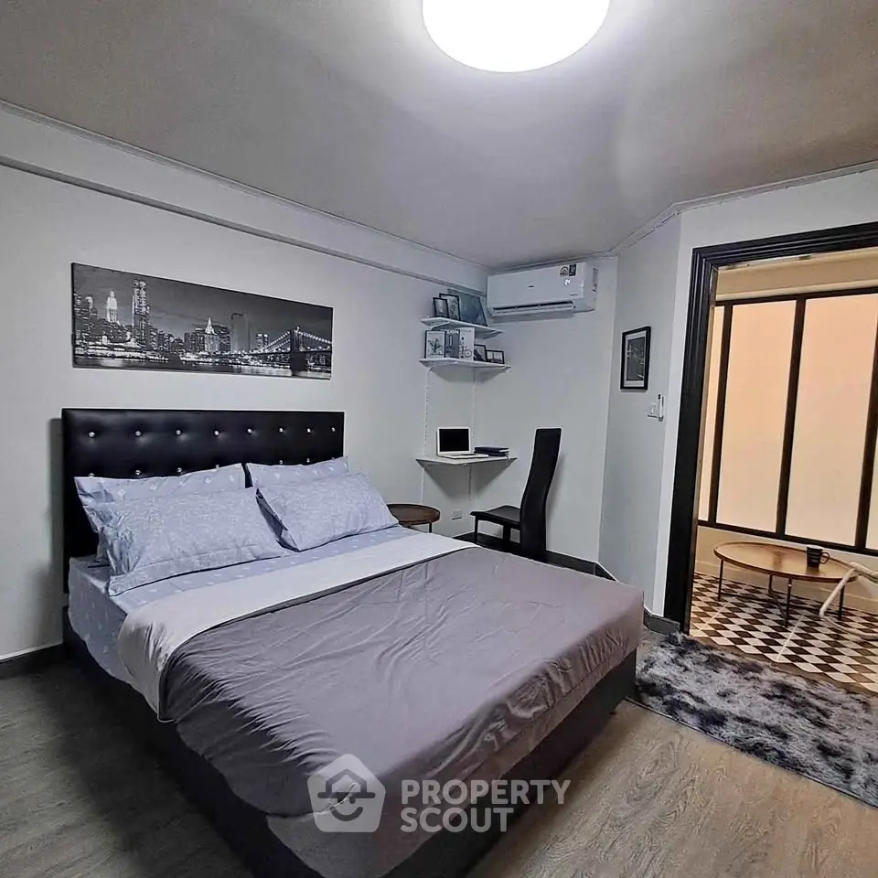 Modern bedroom with stylish decor and workspace, featuring a comfortable bed and sleek flooring.