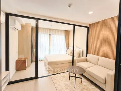 Modern bedroom with glass partition and cozy living area in stylish apartment.