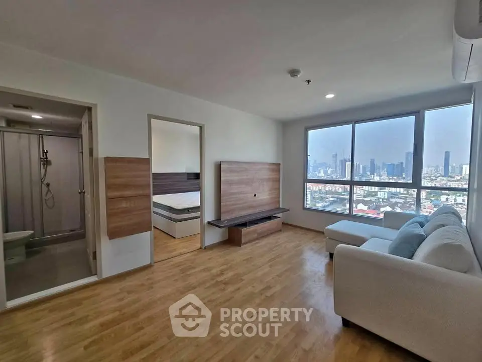 Spacious modern living room with city view, hardwood floors, and stylish furniture in a high-rise apartment.