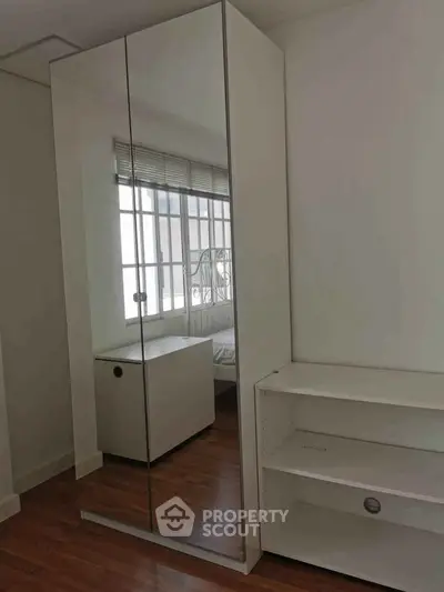 Modern bedroom with mirrored wardrobe and wooden flooring