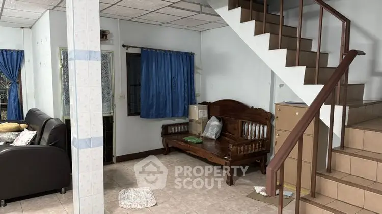 Cozy living room with wooden staircase and classic furniture, ideal for family gatherings.
