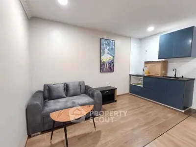 Modern living room with sleek kitchen, stylish sofa, and elegant decor in a contemporary apartment.